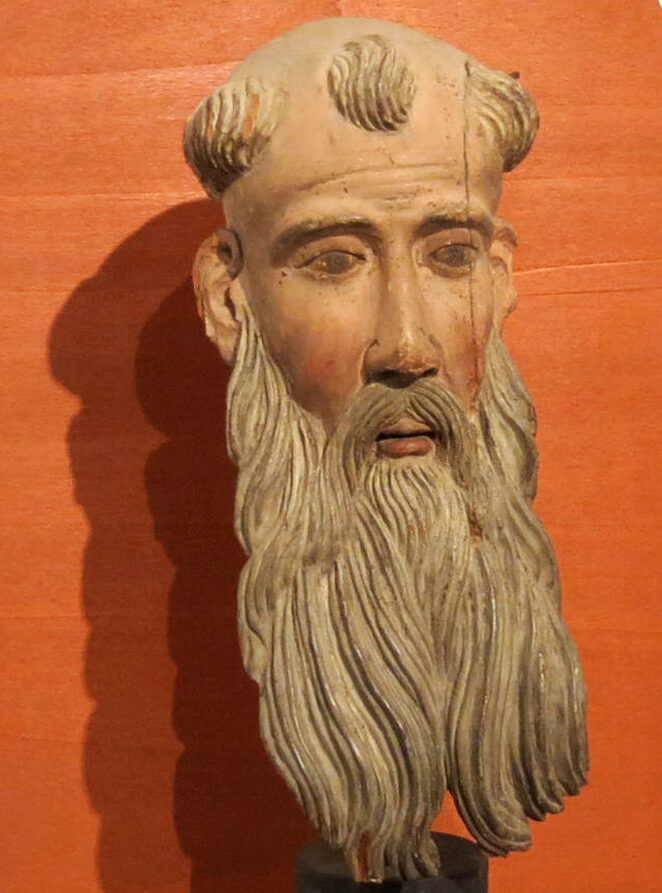 Una testa di uomo con barba molto lunga in pietra