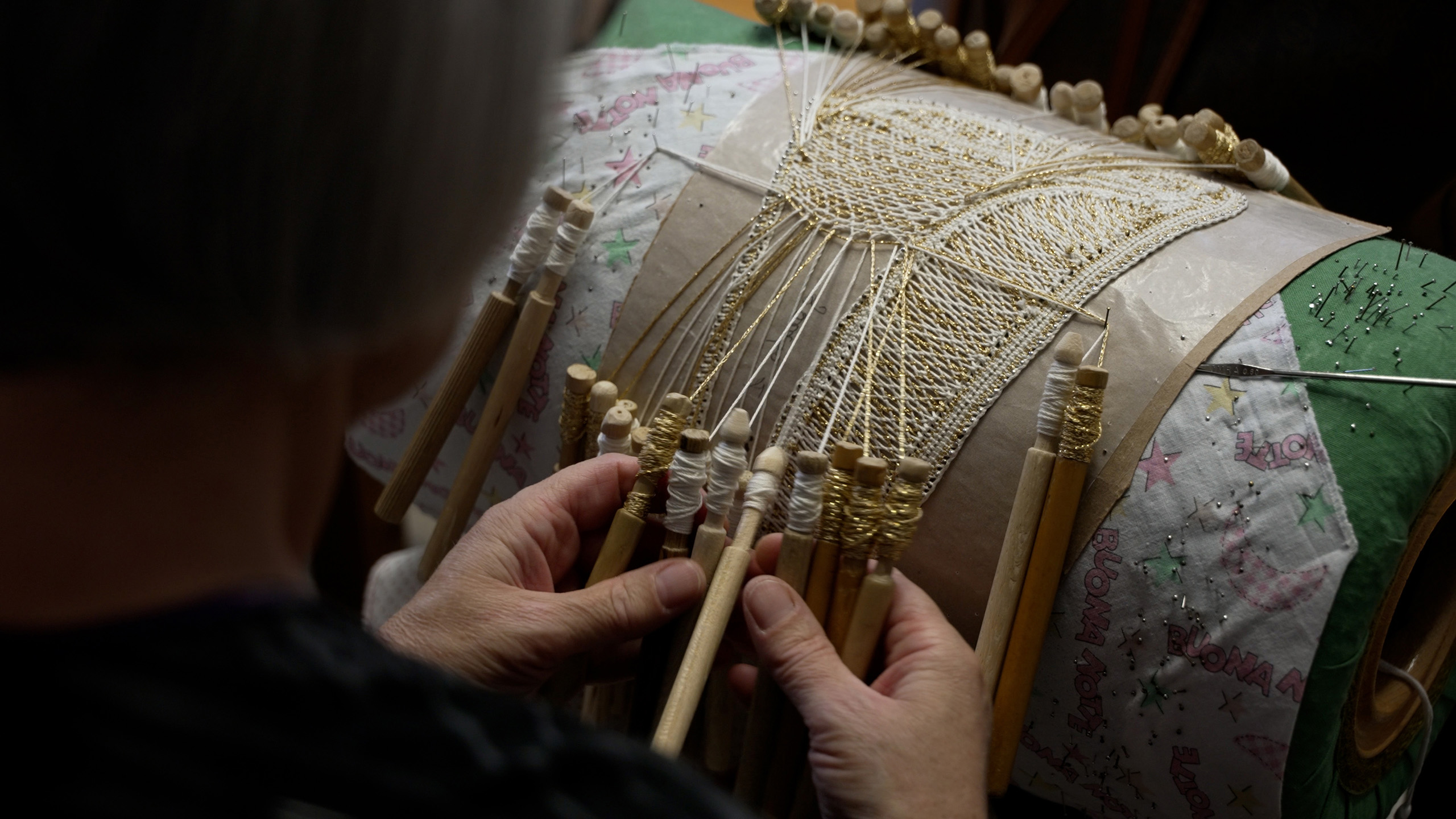 Le mani di una donna che lavorano il tombolo
